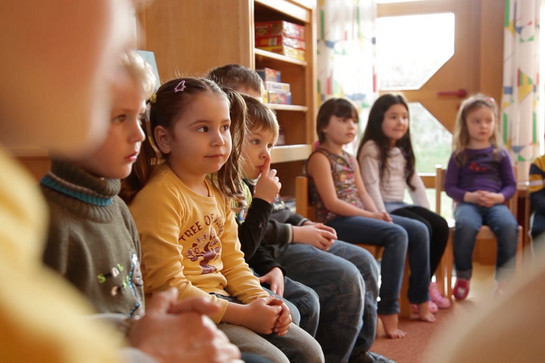 Kindergarten Kinder sitzen im Kreis auf Stühlen