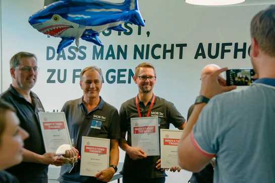 Vier Männer halten vier Preise 