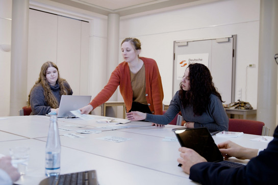 Drei Frauen legen Papiere auf einen Tisch