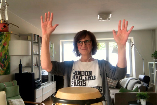 Eine Frau spielt Trommeln in ihrem Wohnzimmer