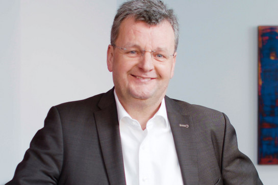 Ein alter Mann mit Brille lacht in die Kamera