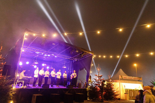 6 Sängerinnen, ein Keyboarder und ein Gitarrist auf einer Weihnachtsmarkt-Bühne