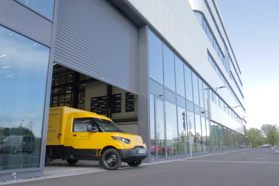 E Auto der deutschen Post fährt aus einer Halle raus