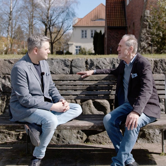 Zwei Männer unterhalten sich auf einer Parkbank