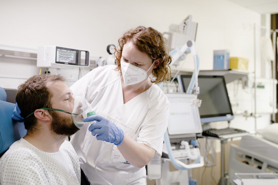 Weibliche Pflegefachkraft hilft Patient mit Sauerstoffmaske