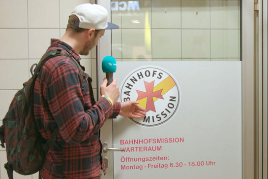 Ein Mann schaut sich die Tür der Bahnhofsmission an