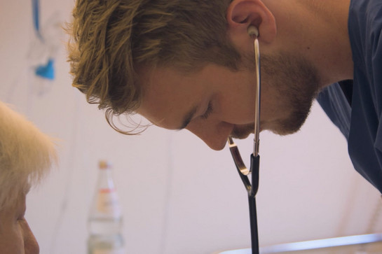 Ein Mann horcht die Lunge einer Patientin ab