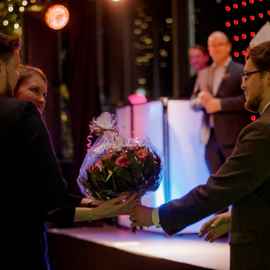 Eine Frau kriegt einen Blumenstrauß überreicht