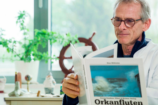 Ein Arzt blättert in einem Buch über Orkanfluten