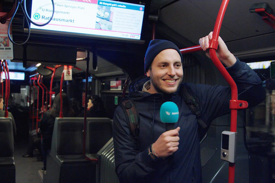 bb_gruppenticket_teaser_06_hauptteaser.jpg Ein Mann mit Mikrofon fährt Abends Bus