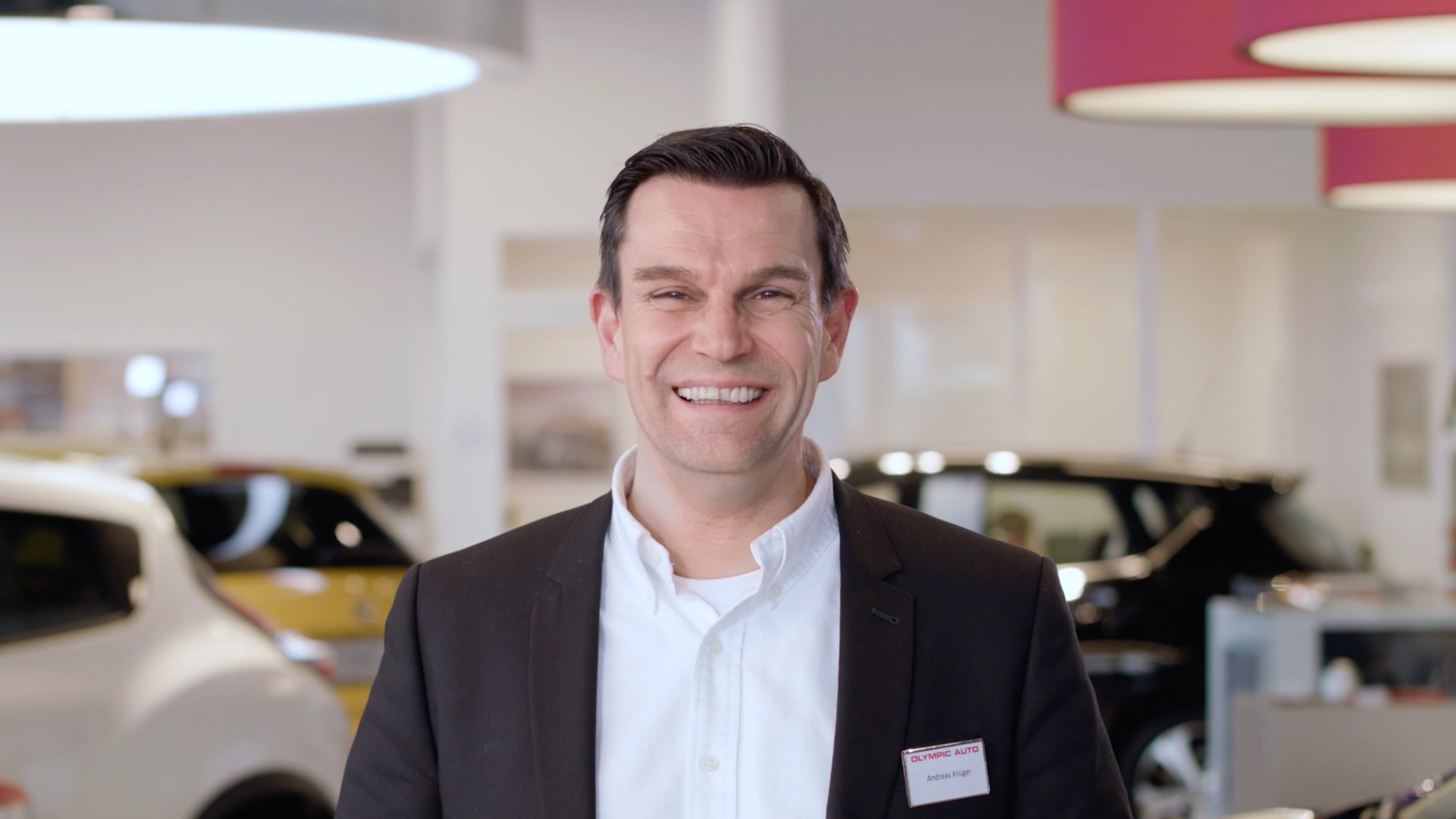 Ein Autoverkäufer lächelt in die Kamera