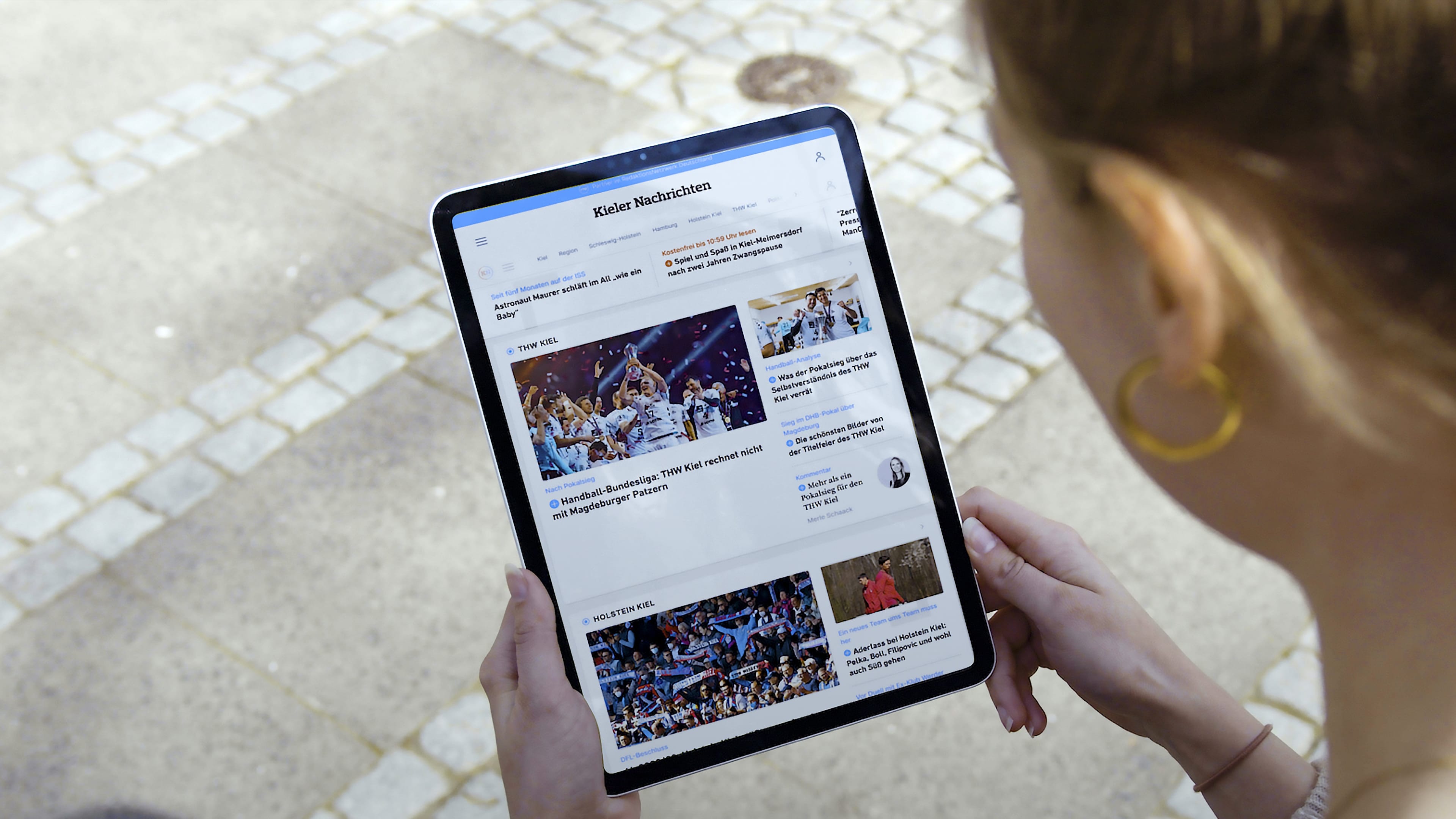 Eine Frau mit einem Tablet, das die Website der Kieler Nachrichten zeigt