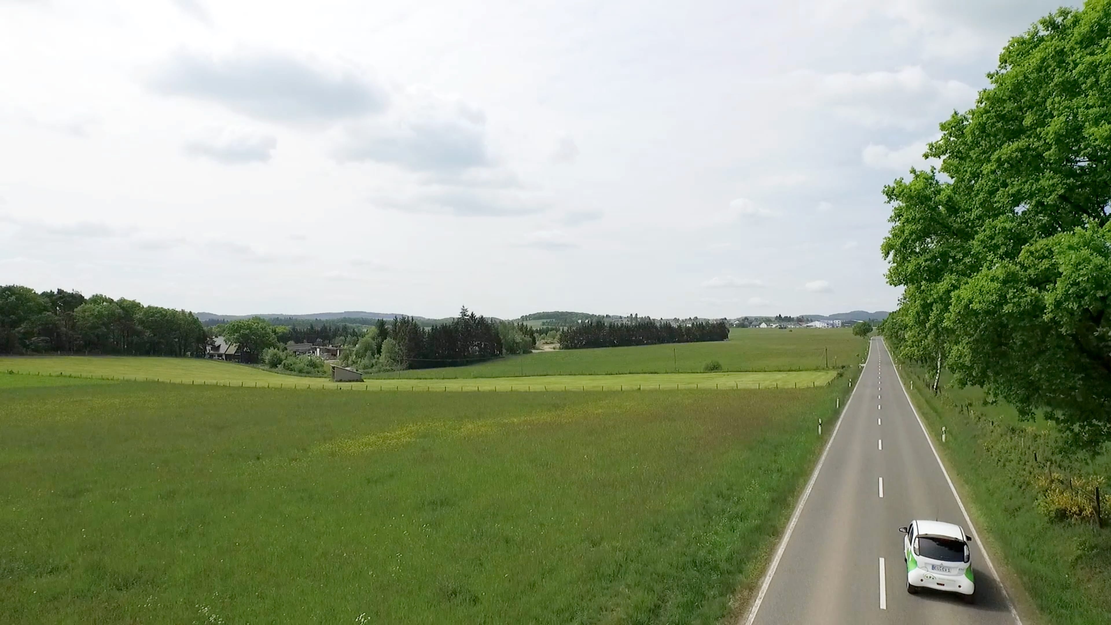 Ein weißes E Auto fährt über eine Landstraße