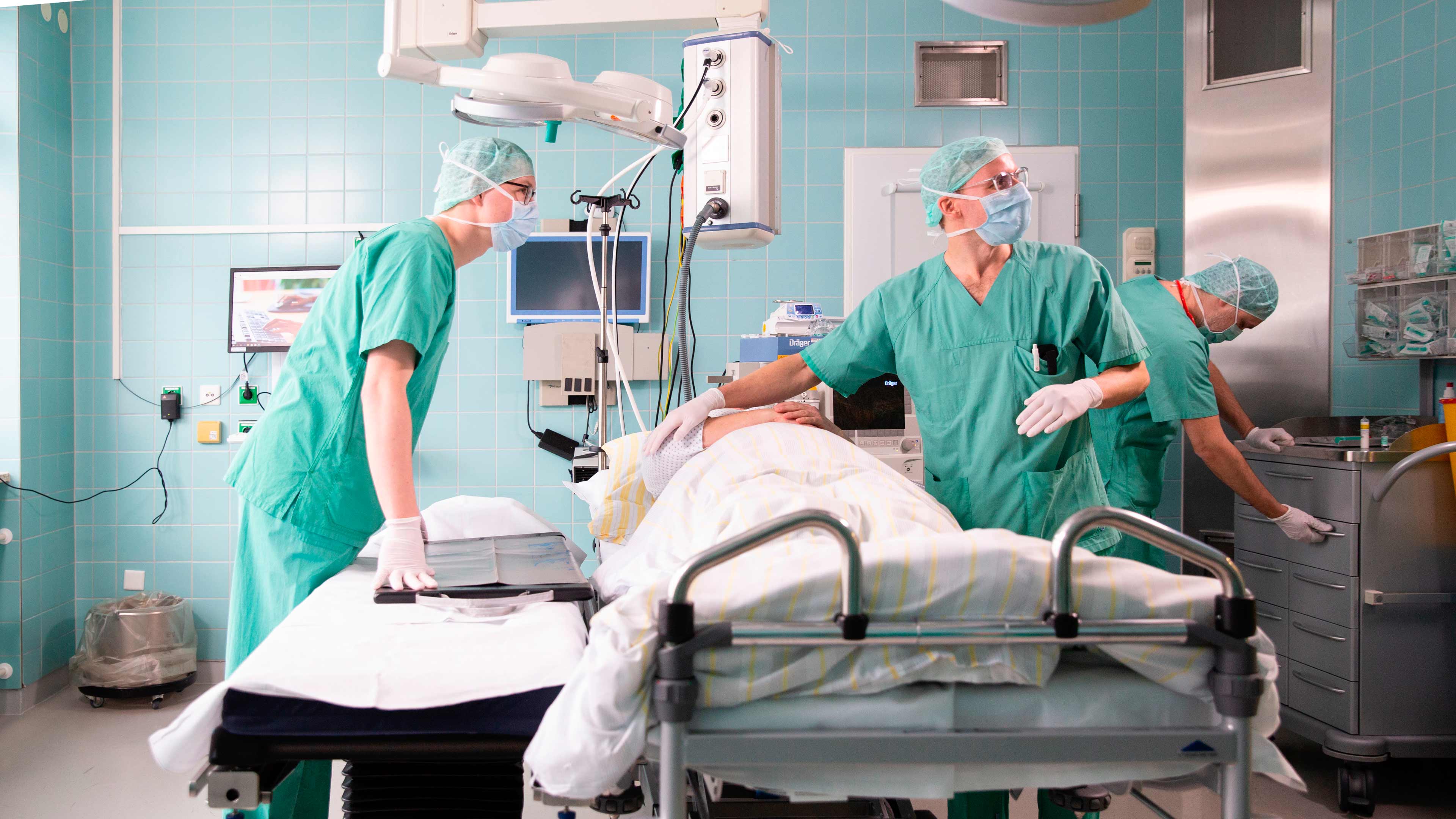 Drei Personen stehen im OP Raum