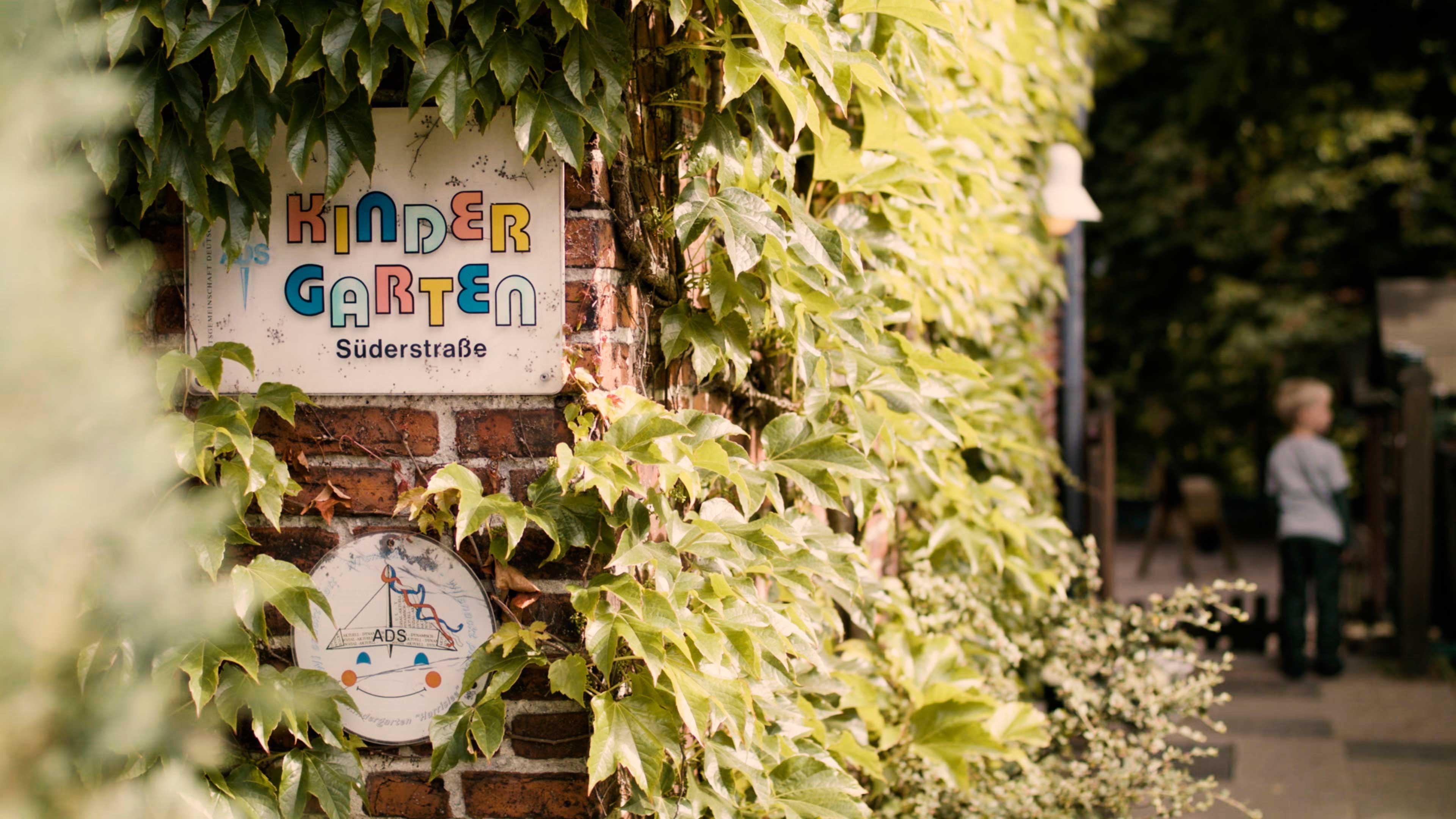 Schild vom ADS Kindergarten an einer bewachsenen Efeu Wand