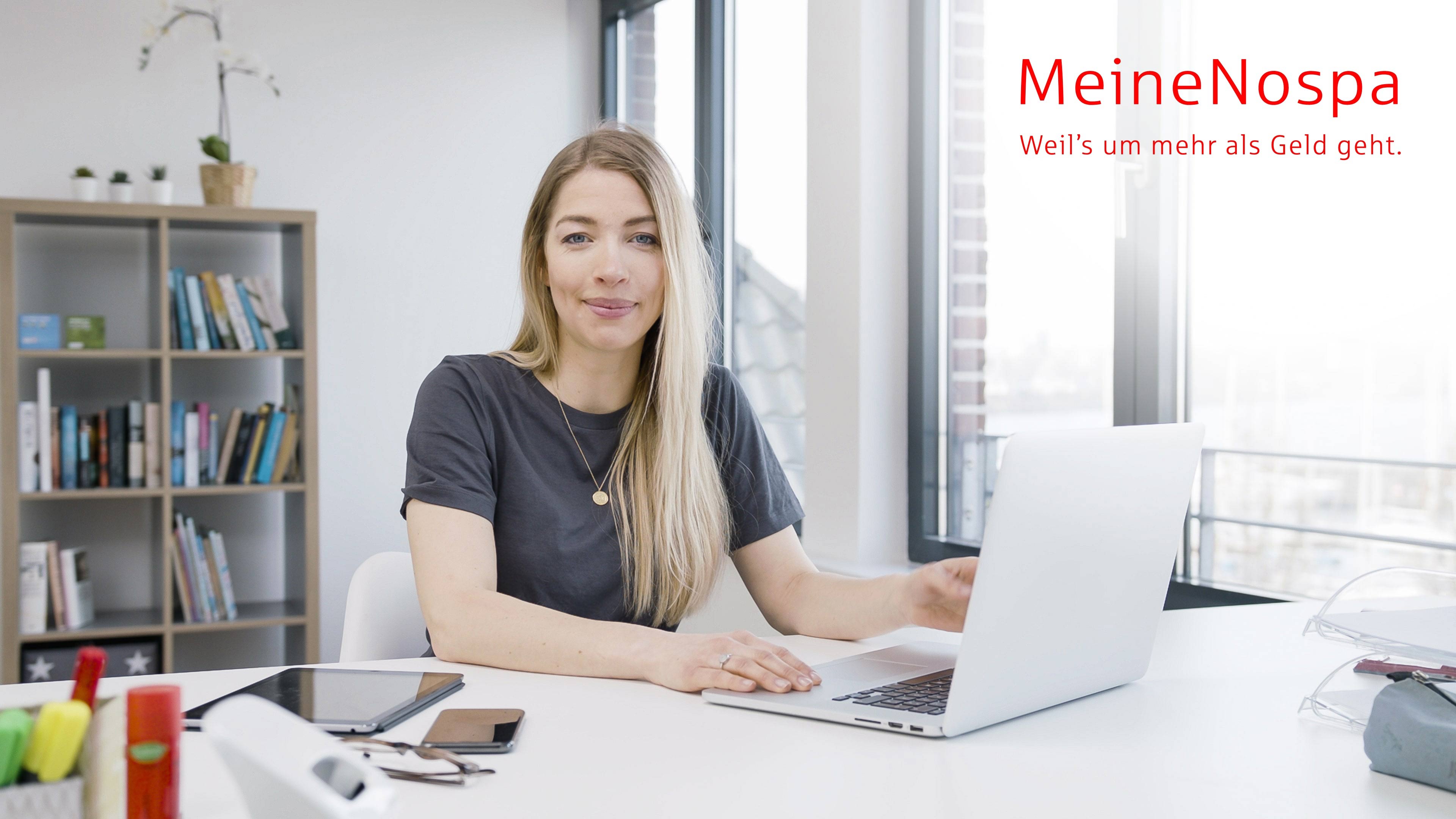 Eine blonde Frau sitzt in ihrem Büro vor einem Laptop
