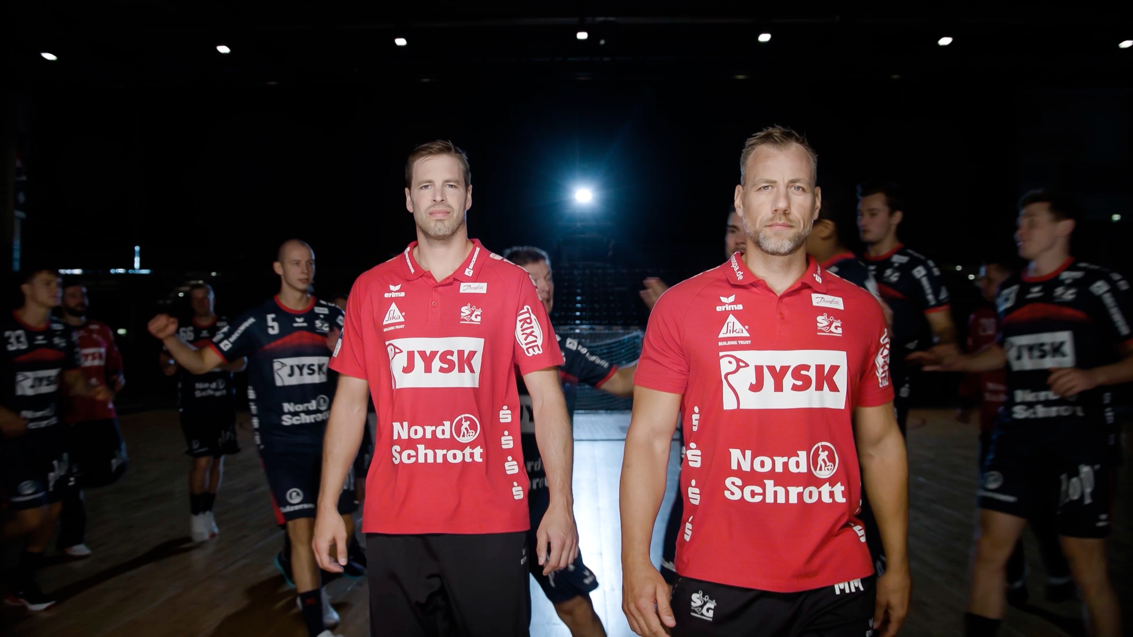 Zwei SG Trainer tragen ein rotes Trikot