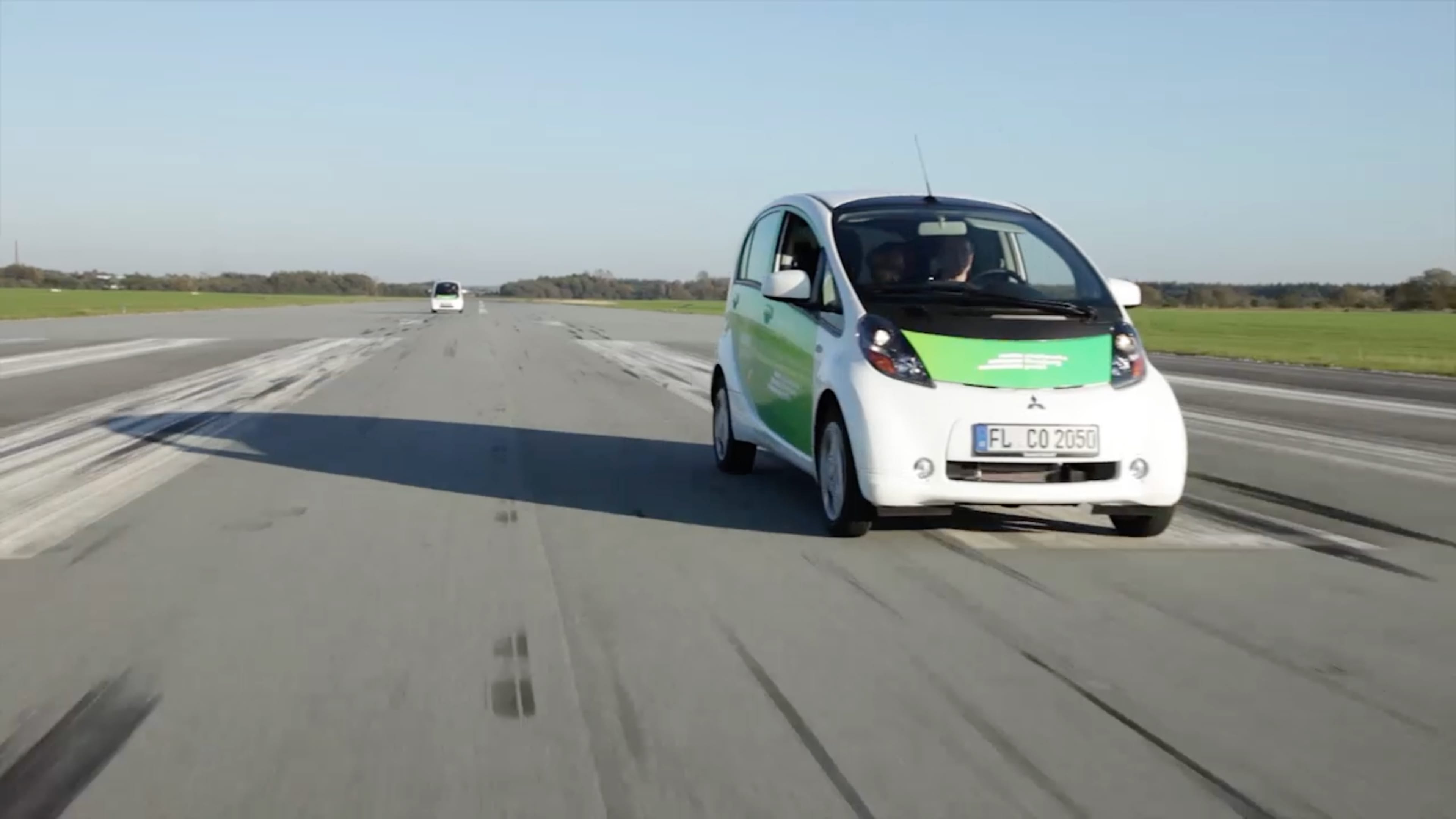 Zwei weiße Autos der Stadtwerke Flensburg fahren auf einer Straße