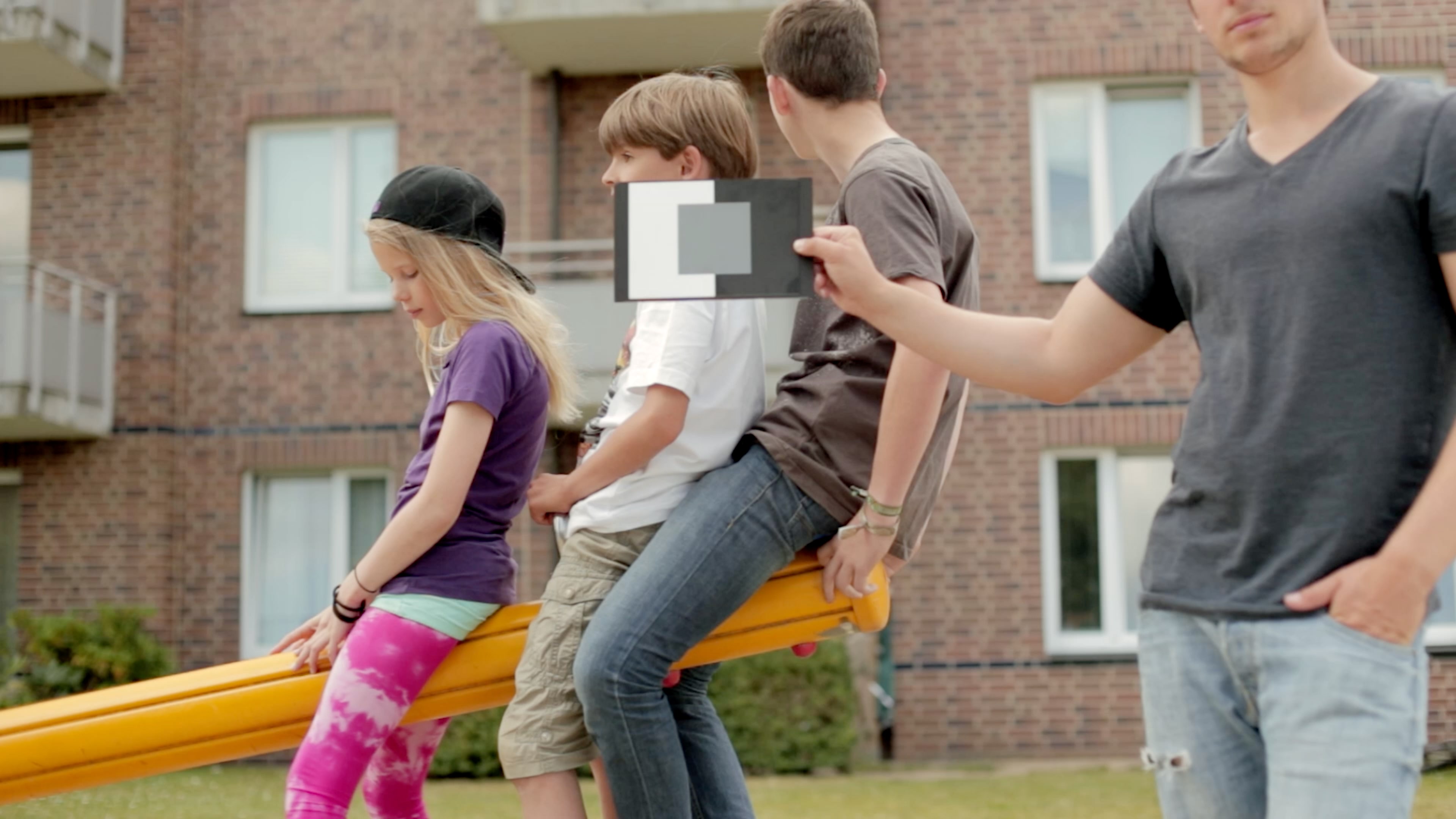 Drei Kinder sitzen auf einer Wippe