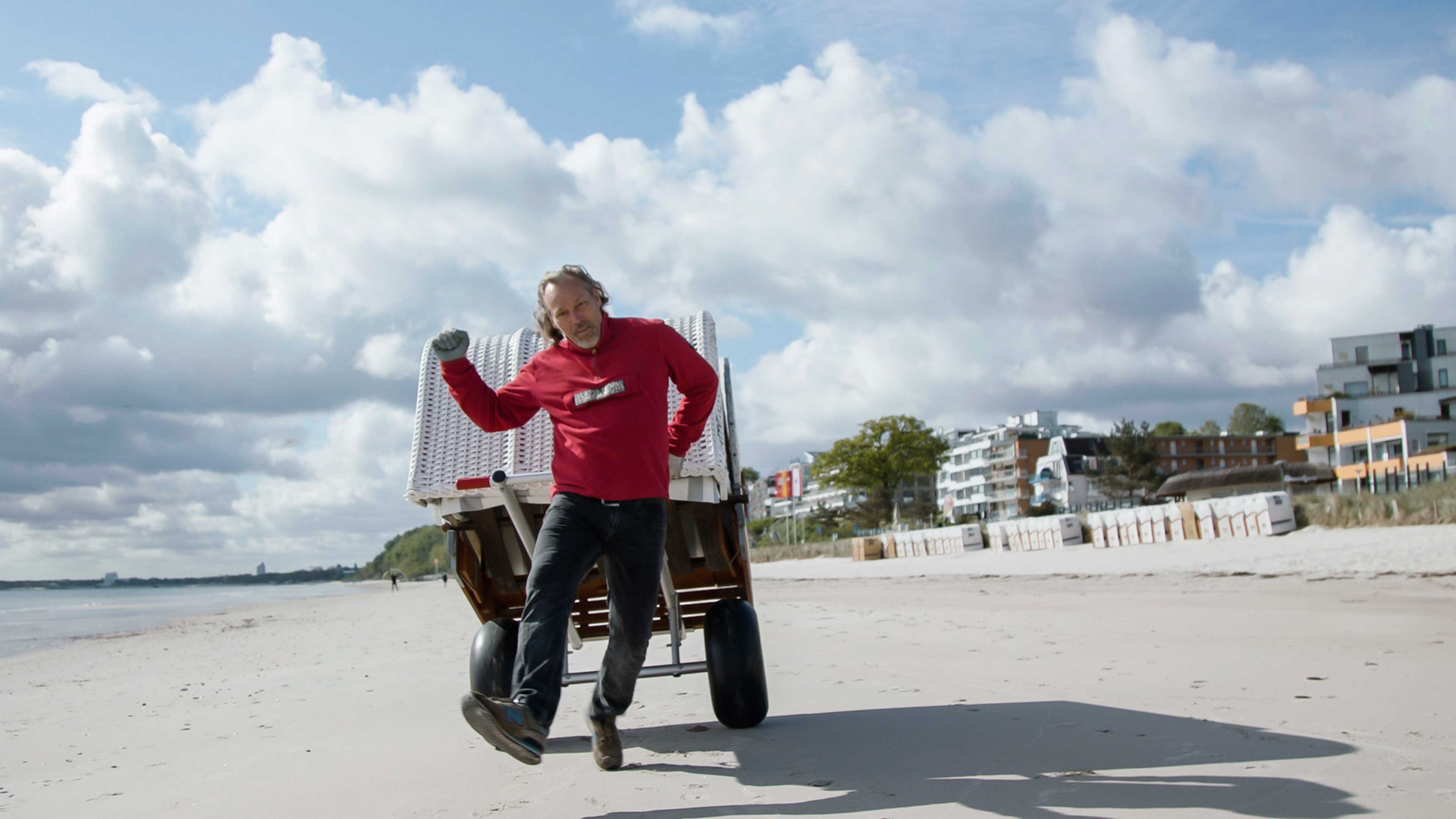 Ein mann schiebt einen Strandkorb am Strand