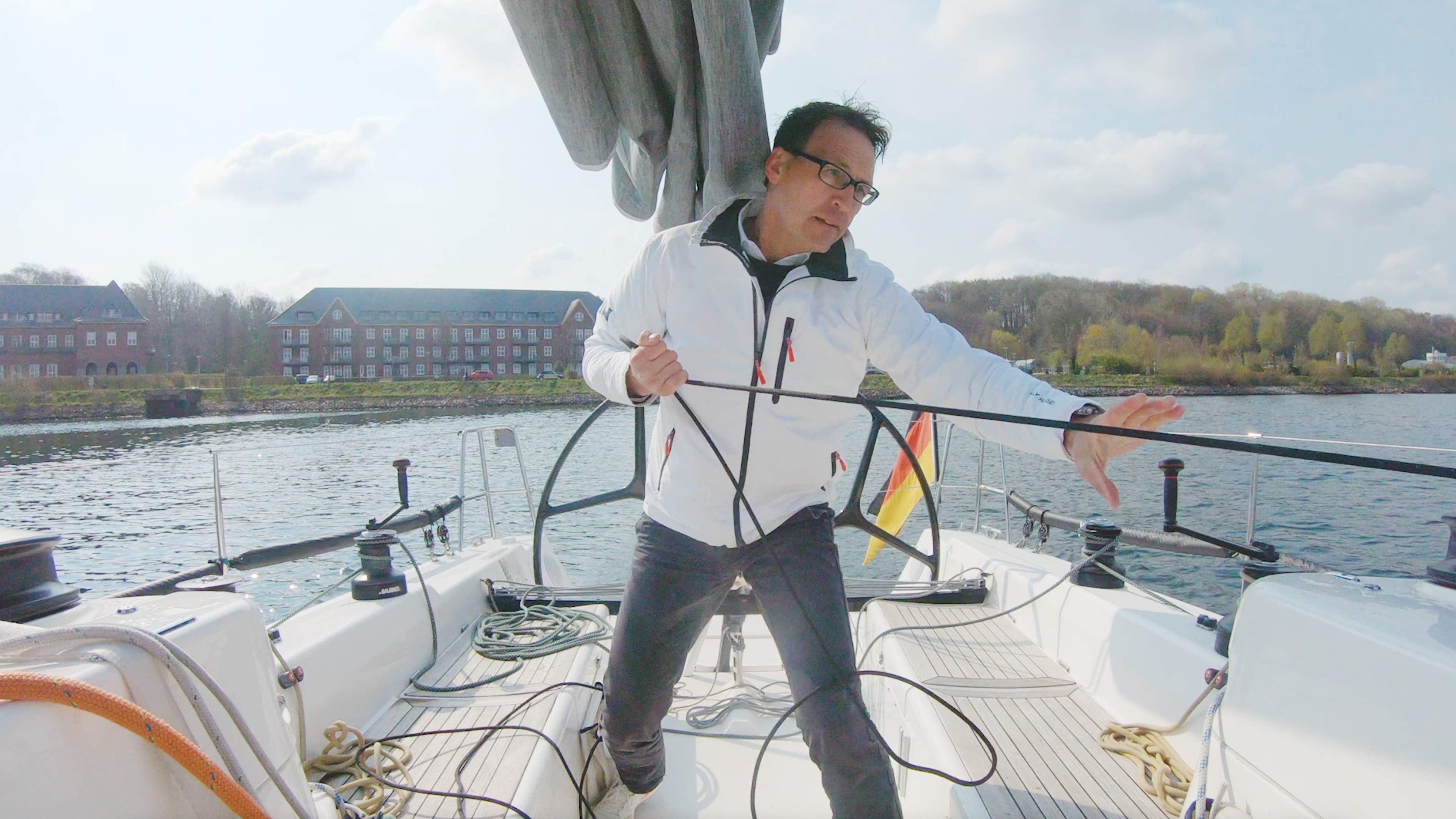 Testimonial Sven Christensen steht vor einem Segelboot, das im Hafen liegt.